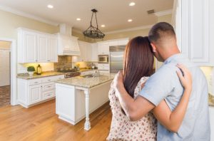 Young couple looking at beautiful kitchen in their finished new home construction.