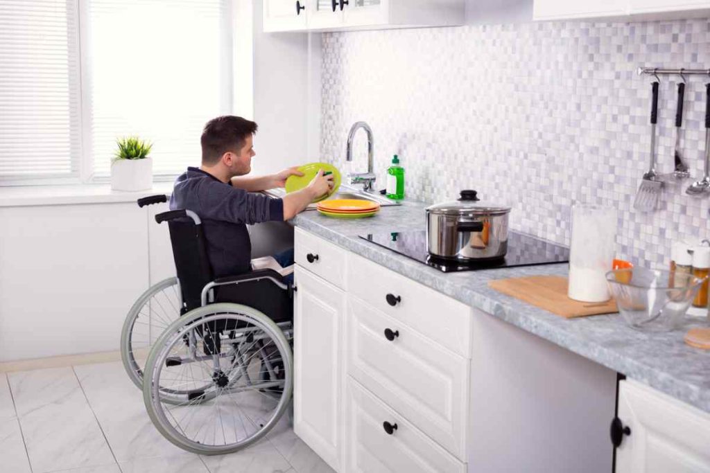 Handicapped man cleaning dishes in an accessible kitchen
