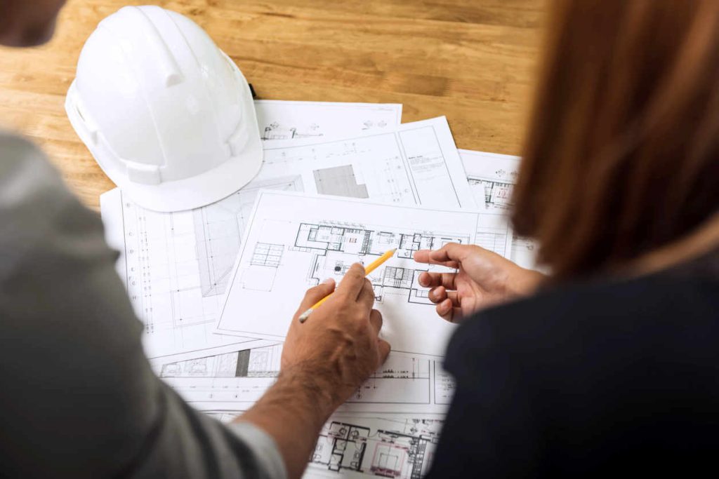Custom home contractor and female client looking over blueprints for new construction